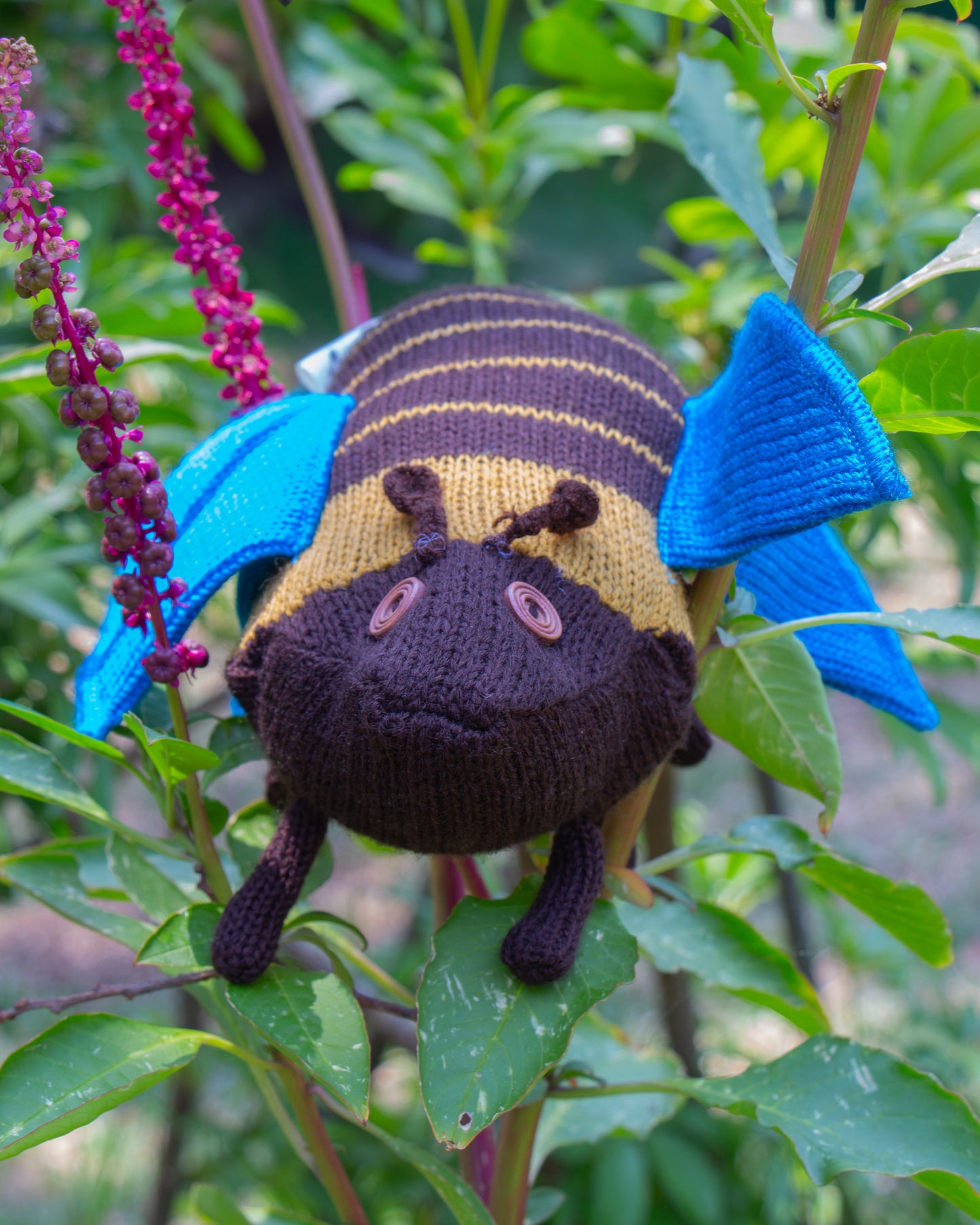 Abeja de peluche entre plantas