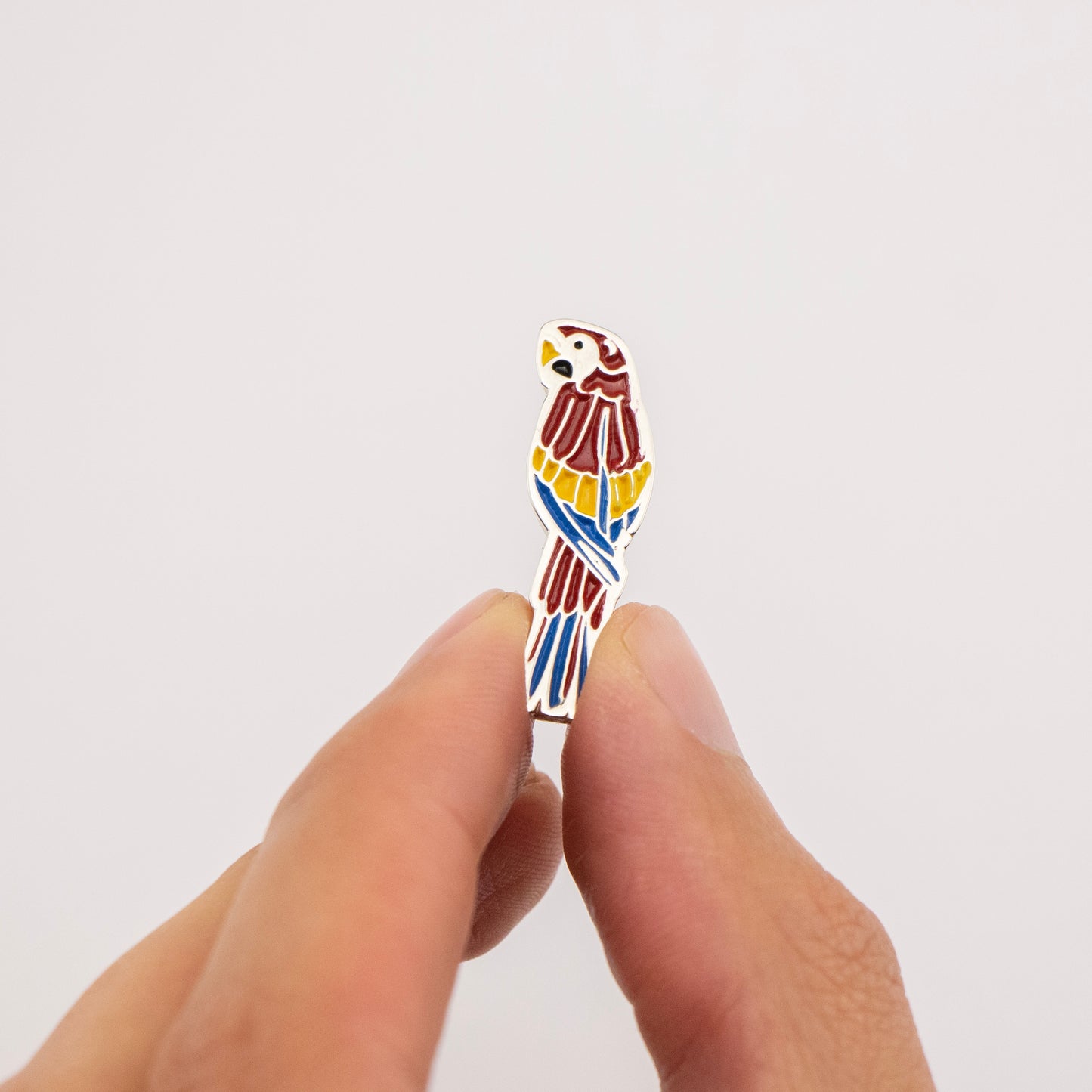 pin guacamaya roja mano