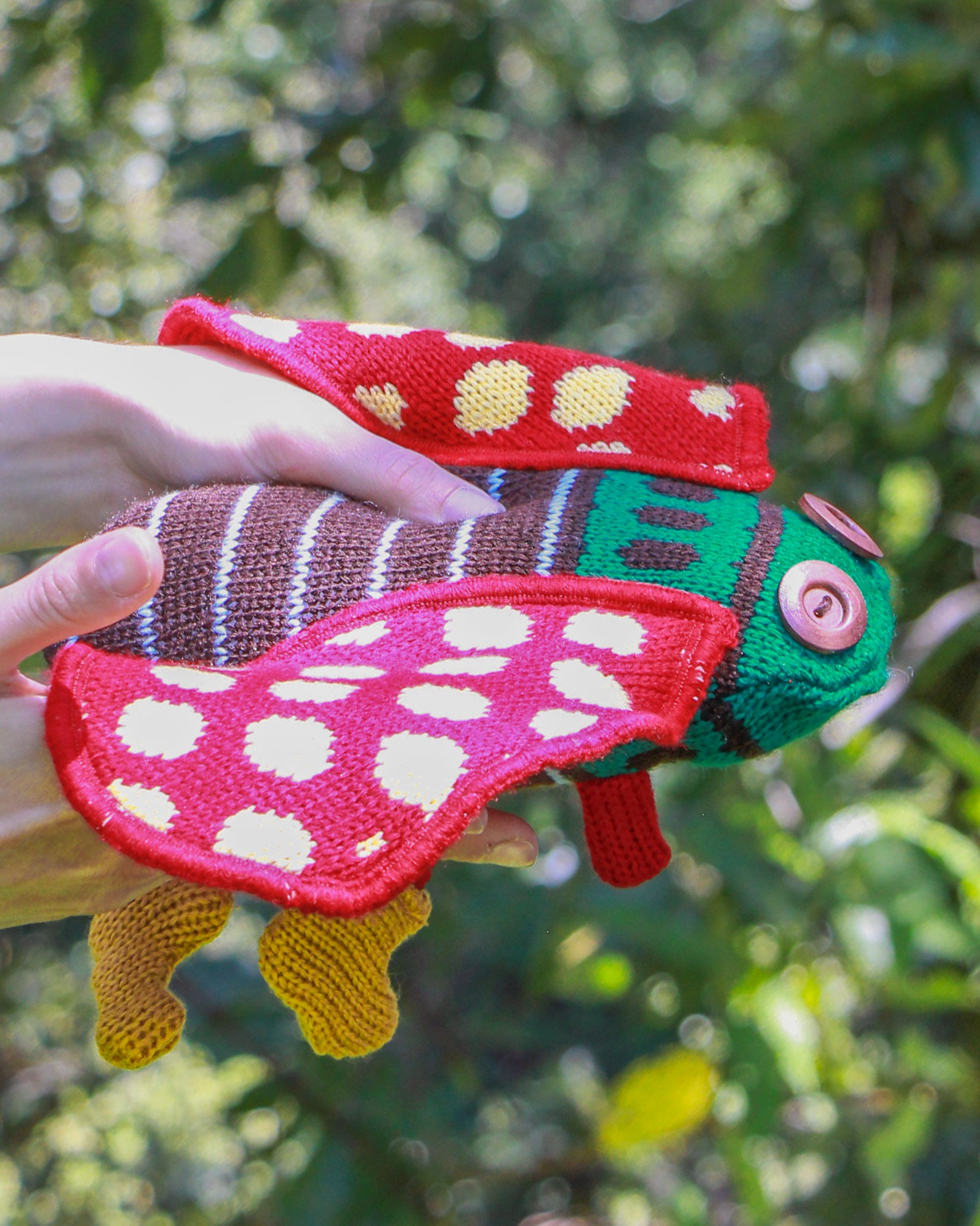 Chicharra de peluche roja en mano